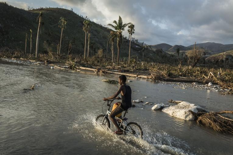 Un garçon roule avec son vélo sur la route inondée après le passage de l’ouragan Matthew. Port Salut sud ouest d’Haiti.