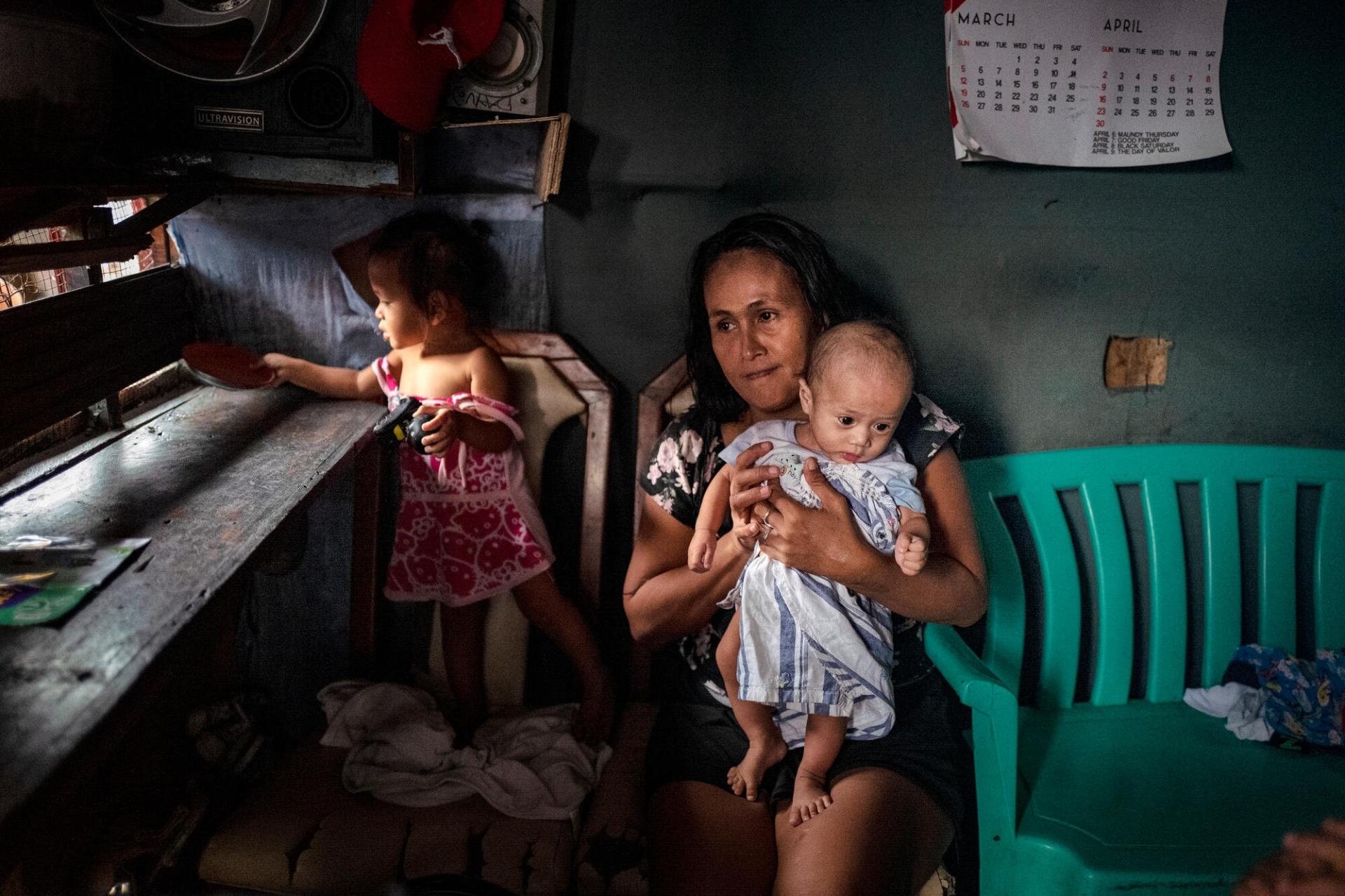 Une mère et ses deux enfants, à leur domicile, lors d'une visite des équipes MSF. Tondo, Manille. Philippines. 13 mars 2023.