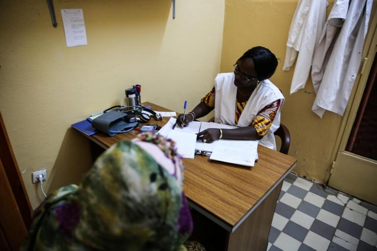 Le Dr. Djénabou Diallo prescrit des médicaments à une patiente âgée de 36 ans, atteinte d'un cancer du sein, dans le service d'hémato-oncologie hôpital du Point G. Les médicaments prescrits sont fournis gratuitement par MSF et comprennent notamment des puissants antidouleurs et des antibiotiques. Mali. 2019.
 © MSF/Mohammad Ghannam
