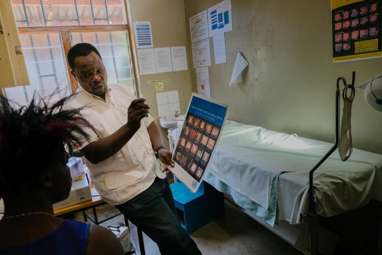 Prince Nkhoma explique le processus de dépistage du cancer du col de l'utérus à une jeune femme de 22 ans dans un dispensaire MSF pour les professionnel.le.s du sexe, intégré à l'hôpital de district de Mwanza. Le risque de développer un cancer du col de l'utérus est particulièrement élevé chez les professionnel.le.s du sexe : une mauvaise utilisation du préservatif et de multiples partenaires sexuels entraînent une transmission plus élevée du virus HP (HPV), qui provoque le cancer du col. Malawi.&nbsp;
 © Isabel Corthier