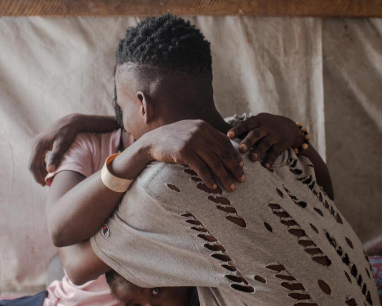 Seember dans les bras de son fils adolescent, dans le camp de personnes déplacées de Mbawa.&nbsp;
 © Kasia Strek