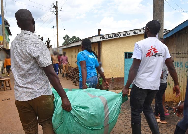 Des membres des équipes MSF, accompagnés d'habitants, transportent des vêtements destinés aux enfants de moins de dix ans.
 © MSF/Lucy Makori