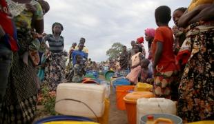 Des dizaines de personnes déplacées patientent après l'approvisionnement de 8 000 litres d'eau par camion dans un espace ouvert à la périphérie de Mueda, 