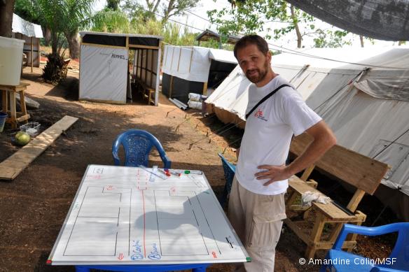 Pascal devant le plan de la structure de prise en charge de l'Ebola à Guéckédou, en Guinée.