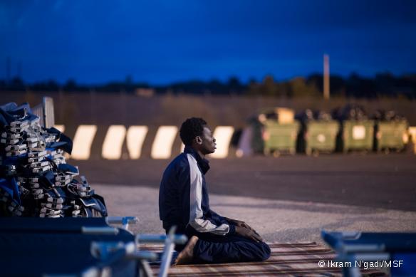 Un jeune homme en provenance de Gambie prie dans le camp de transit de Augusta en Italie, quelqeus heures après avoir été repêché en mer. Septembre 2014.