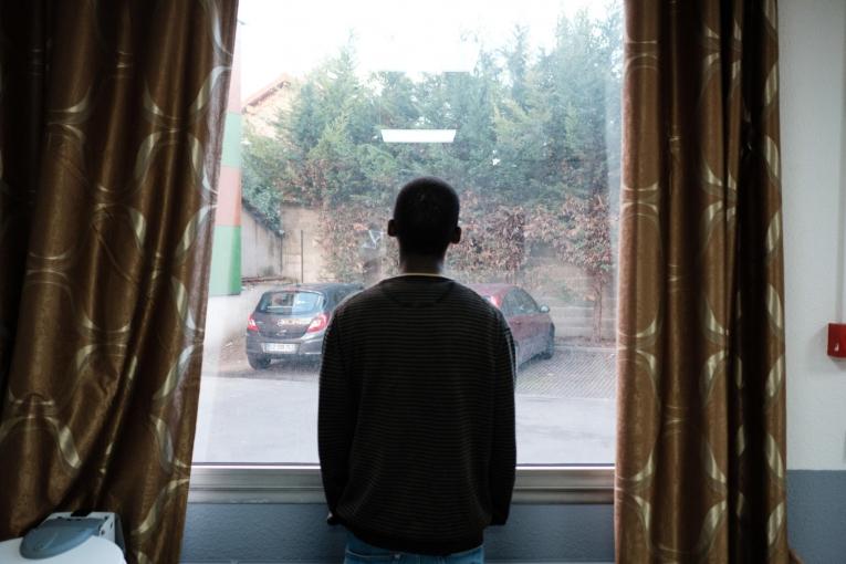 Un jeune bénéficiaire du projet MSF Passerelle regarde par la fenêtre depuis l’hôtel. 2018. France.