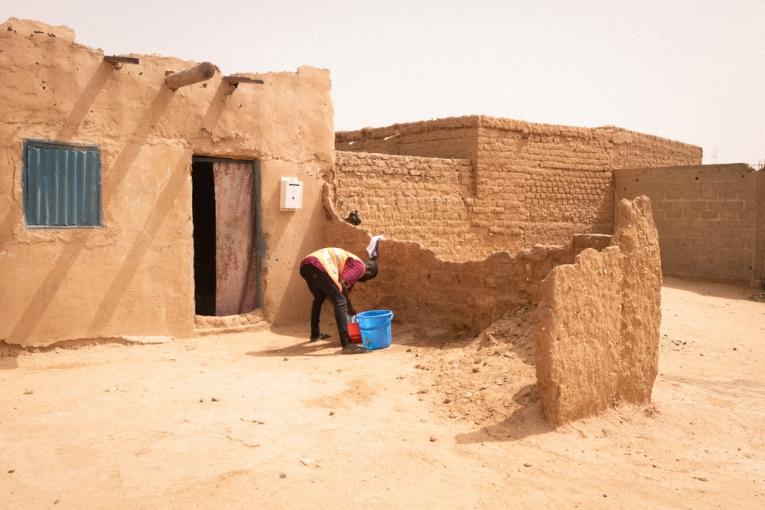 Un migrant lave son linge devant la maison qu'il loue avec d'autres dans un ghetto d'Agadez. Celles et ceux qui passent par Agadez luttent pour trouver un emploi afin de gagner de l'argent pour avoir un endroit où dormir, de la nourriture, et pour continuer leur voyage. 