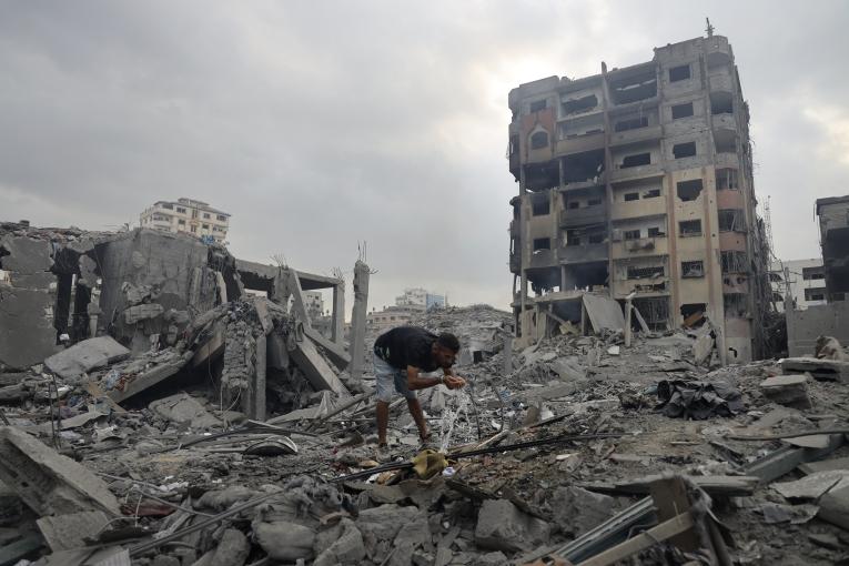 Un homme boit au milieu des décombres à Gaza.
