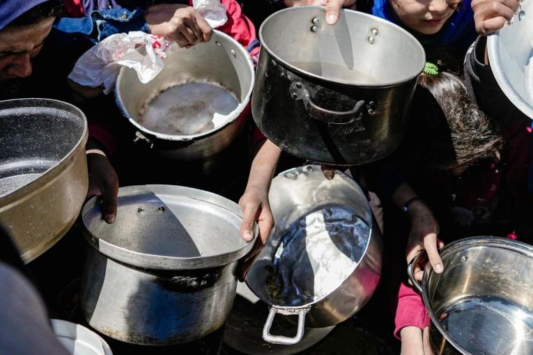 Des enfants tenant leurs pots vides dans une cuisine communautaire dans le nord de Gaza, février 2025
