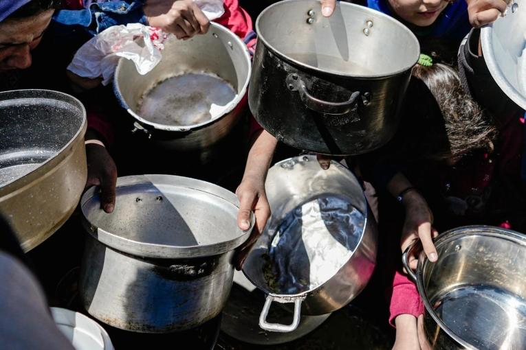 Des enfants tenant leurs pots vides dans une cuisine communautaire dans le nord de Gaza, février 2025 