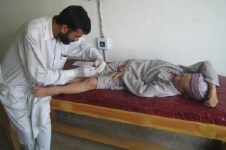 Centre de santé MSF de Darband. Un technicien de laboratoire effectue un prélèvement sur Basit un jeune patient.