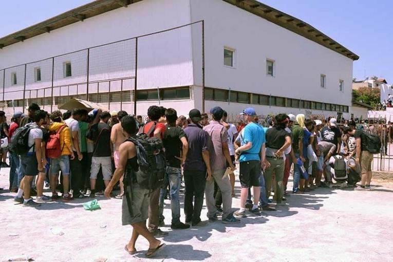 Les migrants font la queue à l'extérieur du stade de Kos en attendant d'être enregistrés par la police grecque.