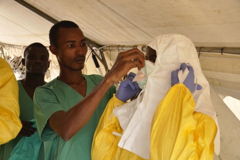 Les membres de l'équipe médicale s'habillent avec des vêtements de protection avant d'entrer dans la structure de soins. 1er avril 2014