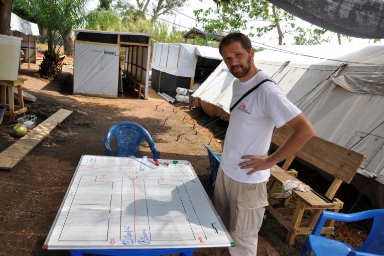 Pascal devant le plan de la structure de prise en charge de l'Ebola à Guéckédou en Guinée.