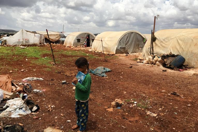 Une jeune Syrienne se tient au milieu d'un camp de personnes déplacées d'Idlib. Syrie. 2018.