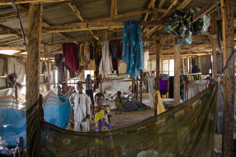 Des enfants dans un abri collectif. 60 à 70 personnes peuvent vivre dans ce type d'abri avant de se voir attribuer un abri personnel pour eux et leur famille. Ils peuvent cependant habiter pendant des mois dans un abri collectif. Bama. Nigeria. 2018.