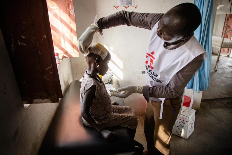 Un membre du personnel MSF examine une jeune fille blessée à la tête dans l'hôpital d'Ulang, dans le nord-est du Soudan du Sud. 2019.