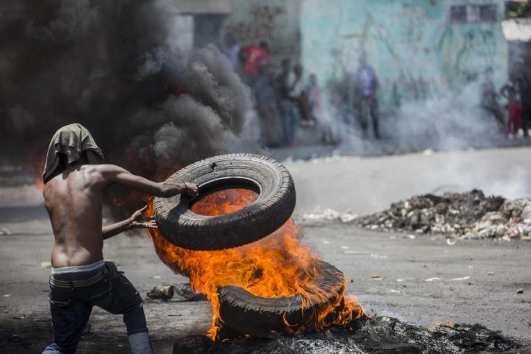 Un manifestant bloque une rue de Port-au-Prince le 13 juin 2019, lors d'une manifestation réclamant le départ du président Jovenel Moïse. Depuis des mois, le pouvoir d'achat des Haïtiens est en baisse constante avec la dévaluation de la monnaie nationale et les prix du carburant ont augmenté. 