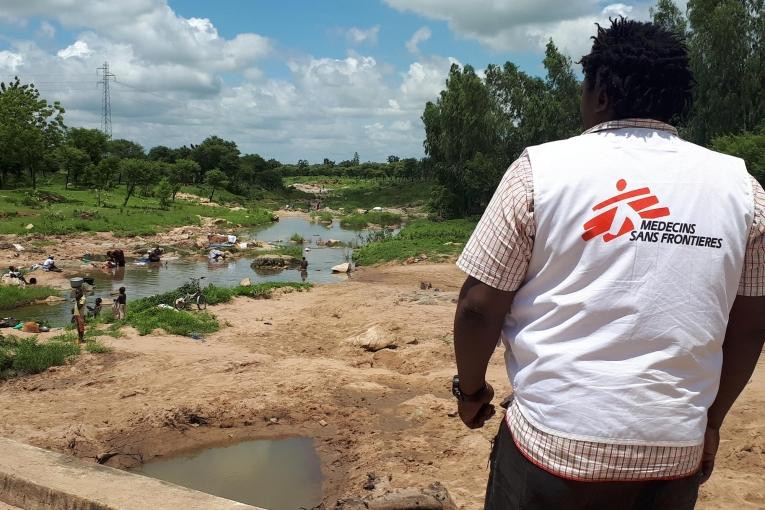 Alphonse Elogo, expert MSF en eau et assainissement, observe un point d'eau potentiellement contaminée dans un quartier du district de santé de Pitoa. 2019. Cameroun. 