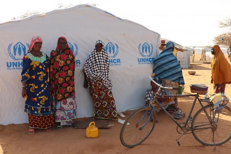 Des femmes se tiennent près d'une tente dans un site de personnes déplacées de la ville de Gorom Gorom. Burkina Faso. 2021.