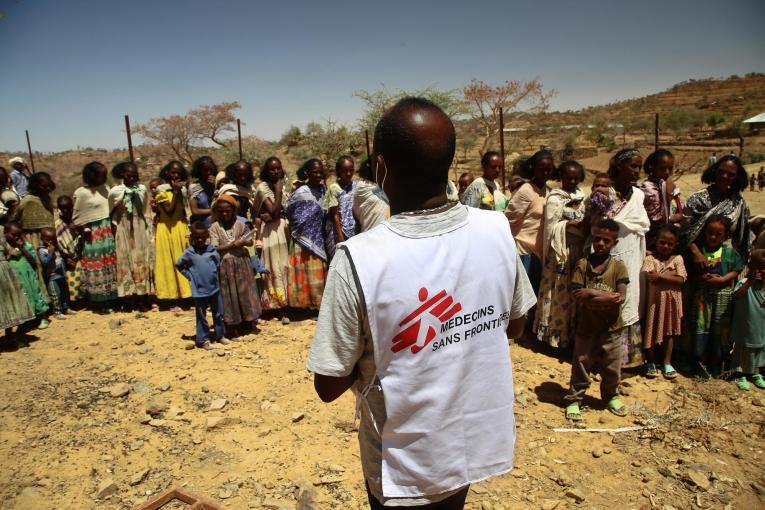 Un employé MSF auprès des femmes qui attendent avec leurs enfants une consultation médicale dans une clinique mobile du village d'Adiftaw, dans la région nord éthiopienne du Tigré.