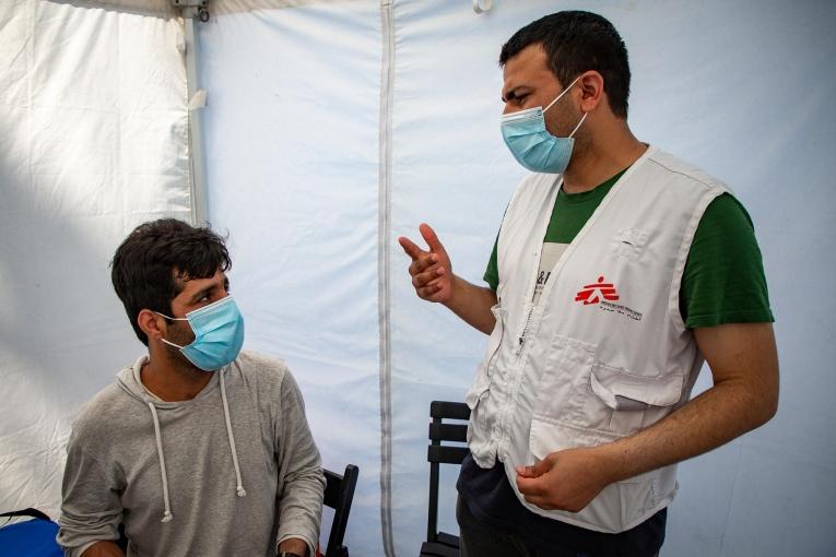 Elias Samim, traducteur MSF, discute avec un patient afghan à la clinique mobile avant sa vaccination contre le Covi-19.