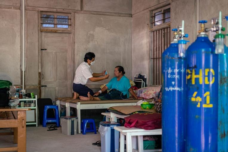 Un membre des équipes MSF au chevet d'une patiente touchée par la Covid-19, dans la clinique MSF de l'État de Kachin. Octobre 2021. Myanmar.