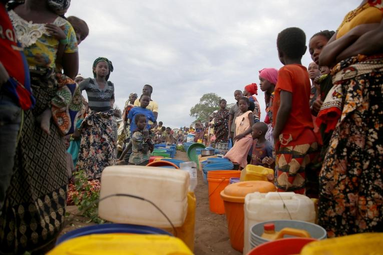 Des dizaines de personnes déplacées patientent après l'approvisionnement de 8 000 litres d'eau par camion dans un espace ouvert à la périphérie de Mueda,