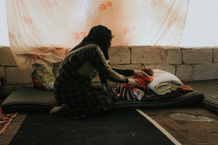 Une femme prend soin de sa fille dans la tente d'un camp de personnes déplacées. Nord-ouest de la Syrie. 2022.