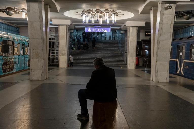 Un homme est assis sur un banc dans le métro. Autour de lui, des wagons où vivent désormais des personnes qui fuit les bombardements à Kharkiv. 11 avril 2022. Ukraine.