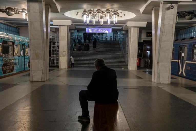 Un homme est assis sur un banc dans le métro. Autour de lui, des wagons où vivent désormais des personnes qui fuit les bombardements à Kharkiv. 11 avril 2022. Ukraine.