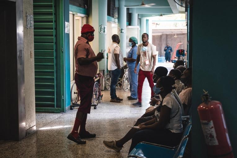 Un membre du personnel soignant parle aux patients dans la zone de triage du centre d'urgence MSF de Turgeau.