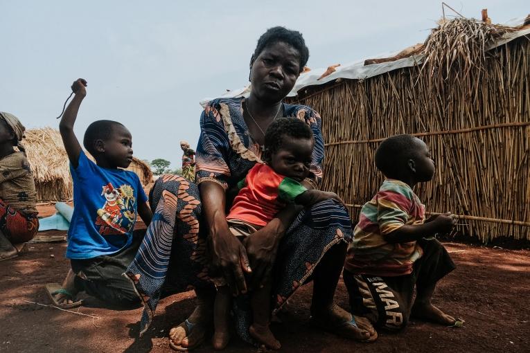 Olga et ses enfants posent devant leur abri du camp de personnes déplacées de Bogouyo. République centrafricaine. 2022.