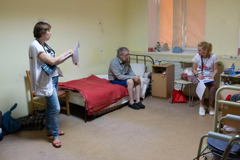 Deux membres des équipes MSF dans la chambre d'un patient qui a trouvé refuge dans un centre pour personnes déplacées à Dnipro. Ukraine. Juin 2022.