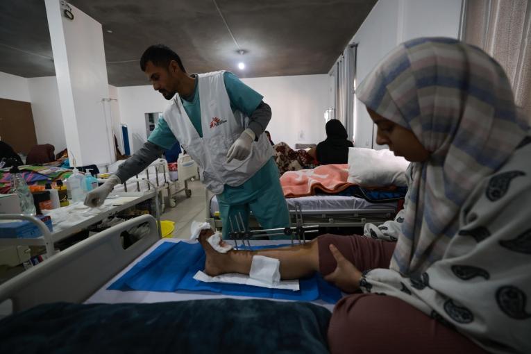 Vue d'une salle d'hospitalisation de l'hôpital indonésien de Rafah avec un membre des équipes MSF et une patiente victime d'une explosion.