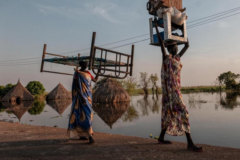 Des femmes transportent des meubles et des marchandises dans une zone inondée de l’État d’Unity.