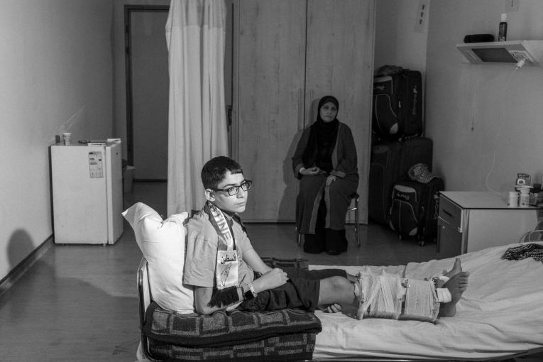 Abdul Rahman sur son lit dans l'hôpital MSF d'Amman, avec sa mère. Août 2024. Jordanie.
