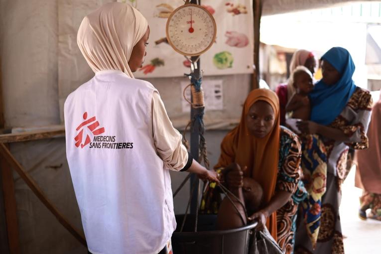 Un membre du personnel MSF prend le poids d'un enfant au centre nutritionnel thérapeutique ambulatoire Kofar Marusa, à Katsina, dans l'État de Katsina.