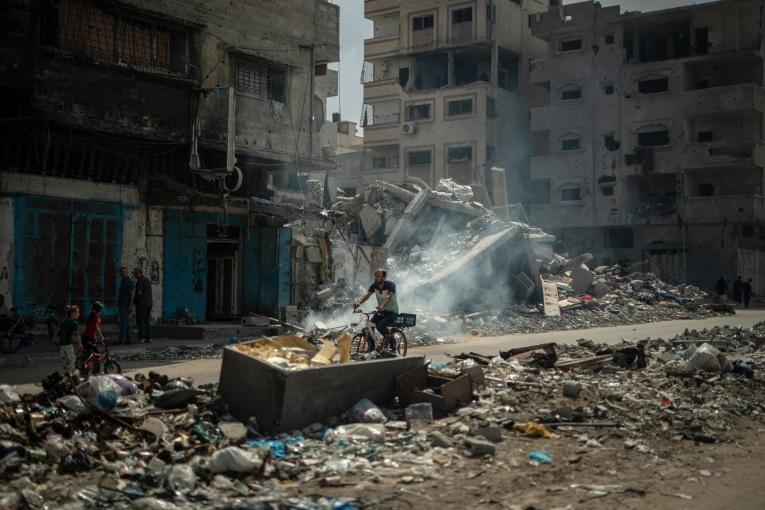 Dans le camp de réfugié d'Al Shate, dans la ville de Gaza, un homme se déplace en bicyclette au milieu des immeubles détruits. Septembre 2024.
