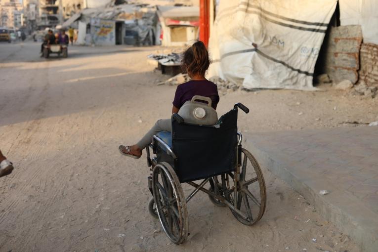Une enfant près d'un fauteuil roulant qu'elle utilise pour transporter des jerricans d'eau, dans la ville de Gaza, en raison de la destruction systématique des infrastructures hydrauliques par Israël.