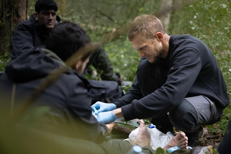 Un secouriste soigne les blessures d'une personne migrante, dans la forêt de Bialovèse en 2024.