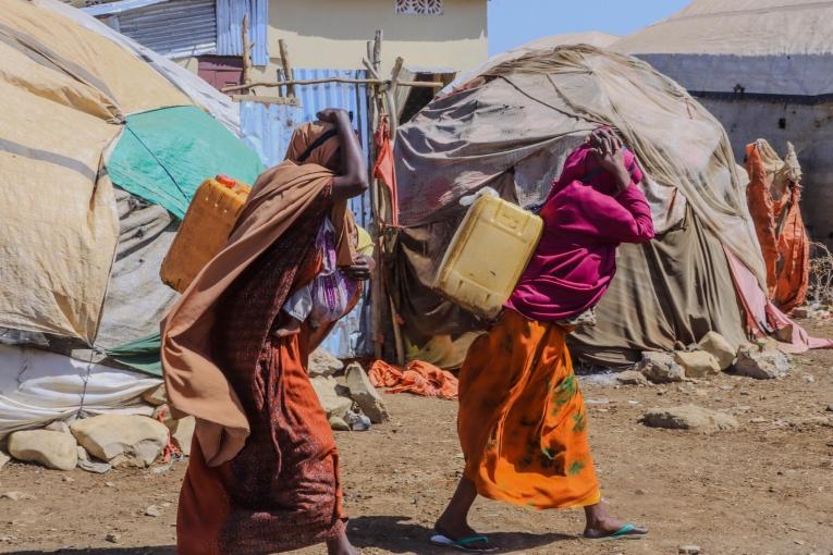Des femmes transportent des bidons alors qu'elles reviennent du point de distribution d'eau du camp de personnes déplacées de Banban, à Baidoa, en Somalie.