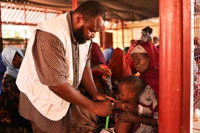 Un membre du personnel de MSF mesure la circonférence du bras à mi-hauteur de Maniru, âgé de 2 ans, au centre de nutrition thérapeutique ambulatoire situé dans l'État de Kebbi, au nord-ouest du Nigeria.