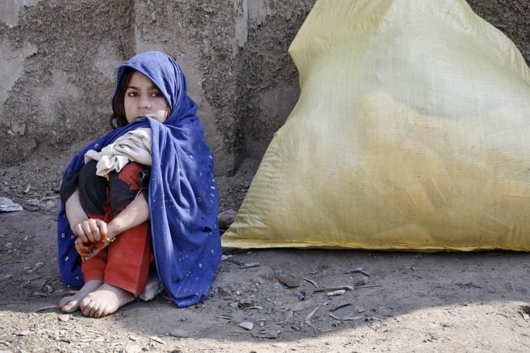 Une petite fille assise près des objets de première nécessité que sa famille a reçu via une distribution de MSF à Peshawar au Pakistan en 2009.