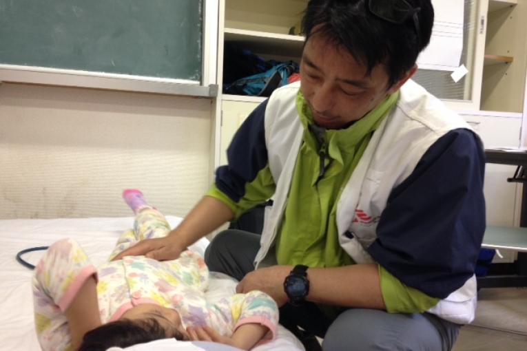 Dans la clinique d'Hakusui Hiroyuki Kato médecin pour MSF prend en charge une fillette de 4 ans souffrant de douleurs à l’estomac.