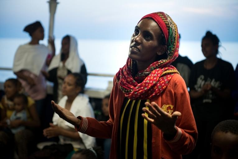 Une femme érythréenne chante une prière avec d'autres femmes et enfants après avoir été secourue le 2 septembre 2015 en mer Méditerranée par le MY Phoenix bateau de recherche et de sauvetage de MSF.
