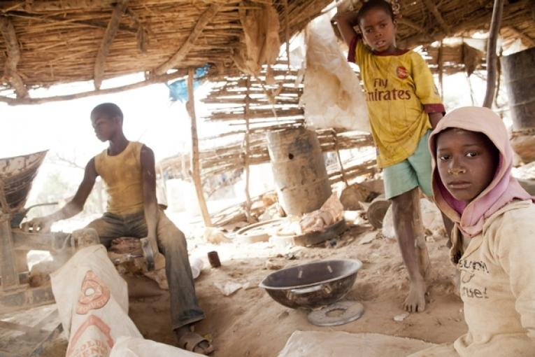 Des enfants travaillent dans un site d’extraction d’or à Bagega. Ibrahim (à droite) 10 ans doit alimenter la broyeuse avec les pierres concassées.
