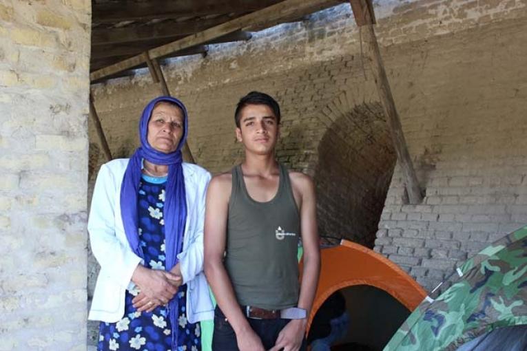 Haseeb 13 ans et sa mère Zubida debout au milieu des tentes abandonnées des réfugiés dans l’ancienne briqueterie de Subotica en Serbie.