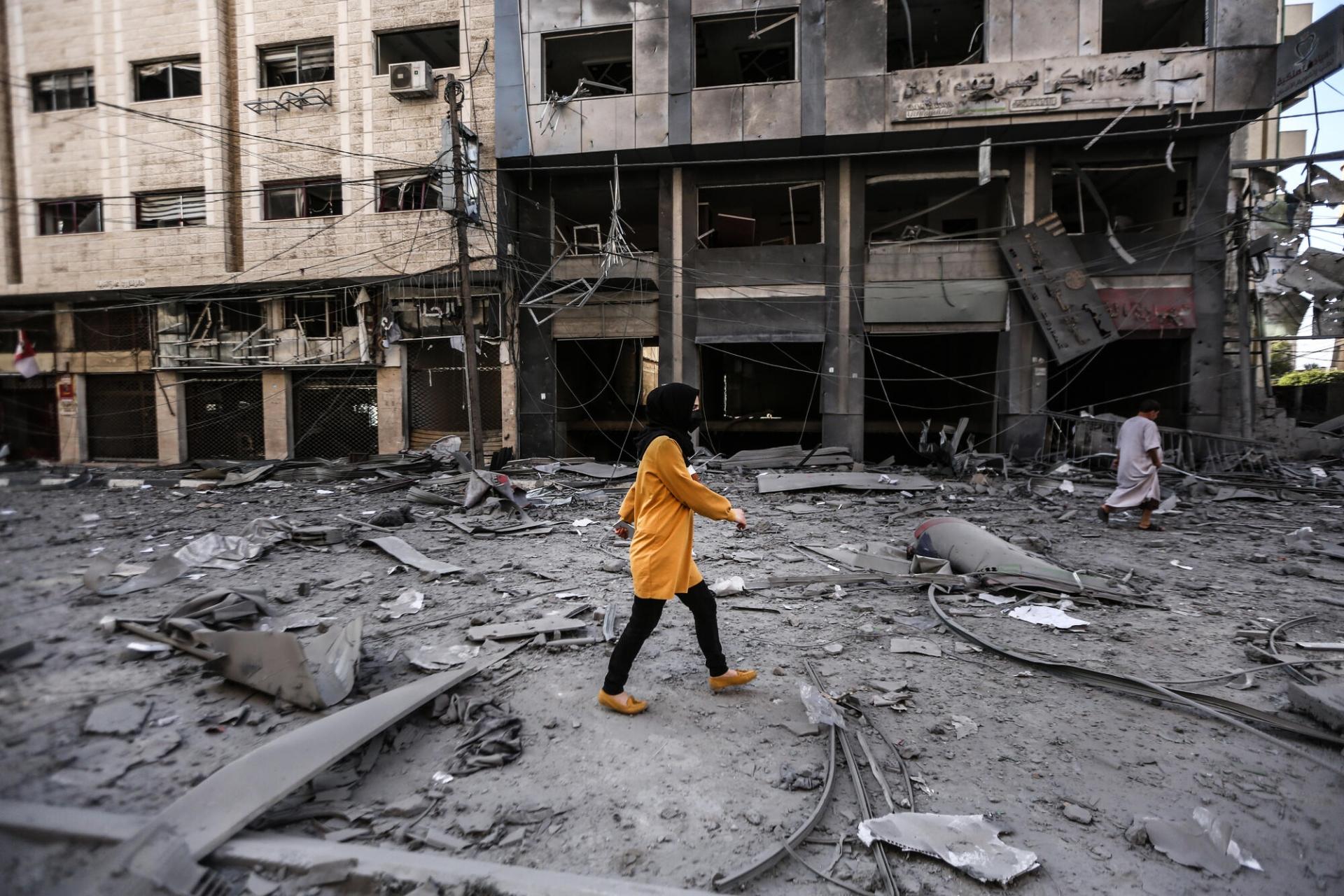 (gauche) À Gaza, une jeune femme marche dans les décombres d’un immeuble partiellement détruit par un bombardement aérien. (droite) Un homme âgé se tient debout au milieu des ruines de son quartier à Gaza. Onze jours de frappes israéliennes massives, de nuit comme de jour, ont causé des dégâts immenses dans l’enclave au mois de mai. 