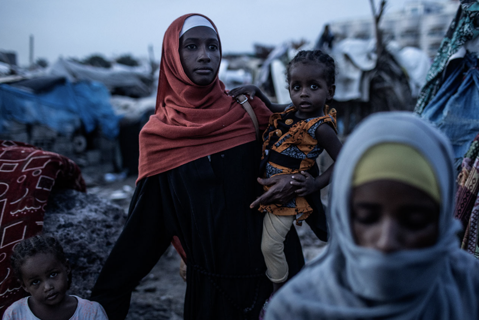 Une femme marche avec un enfant dans un camp informel de réfugiés à Aden, dans le sud du Yémen.